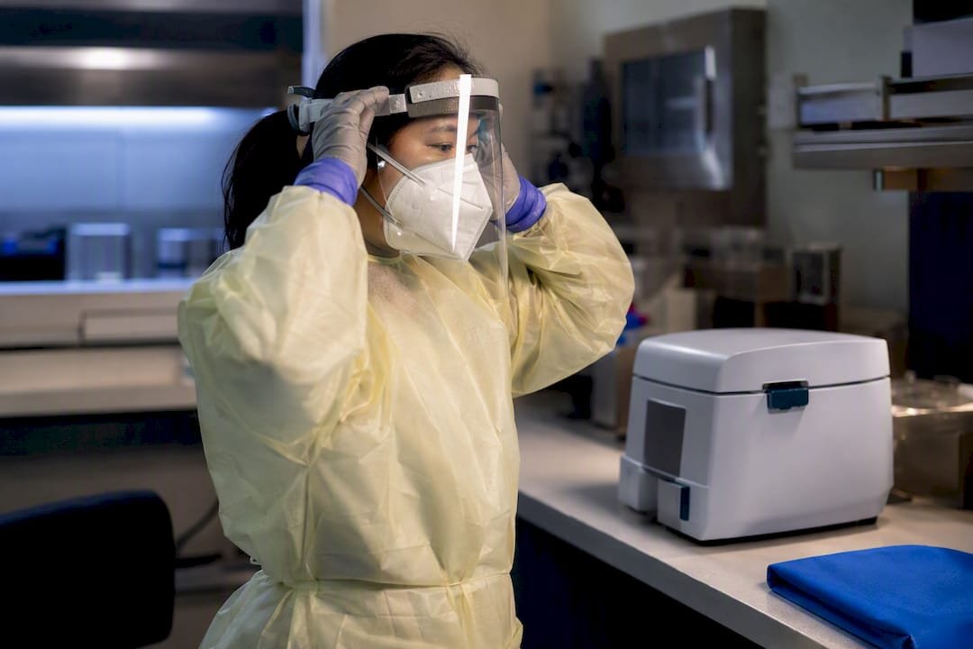 Technician donning enhanced PPE before aerosol procedure